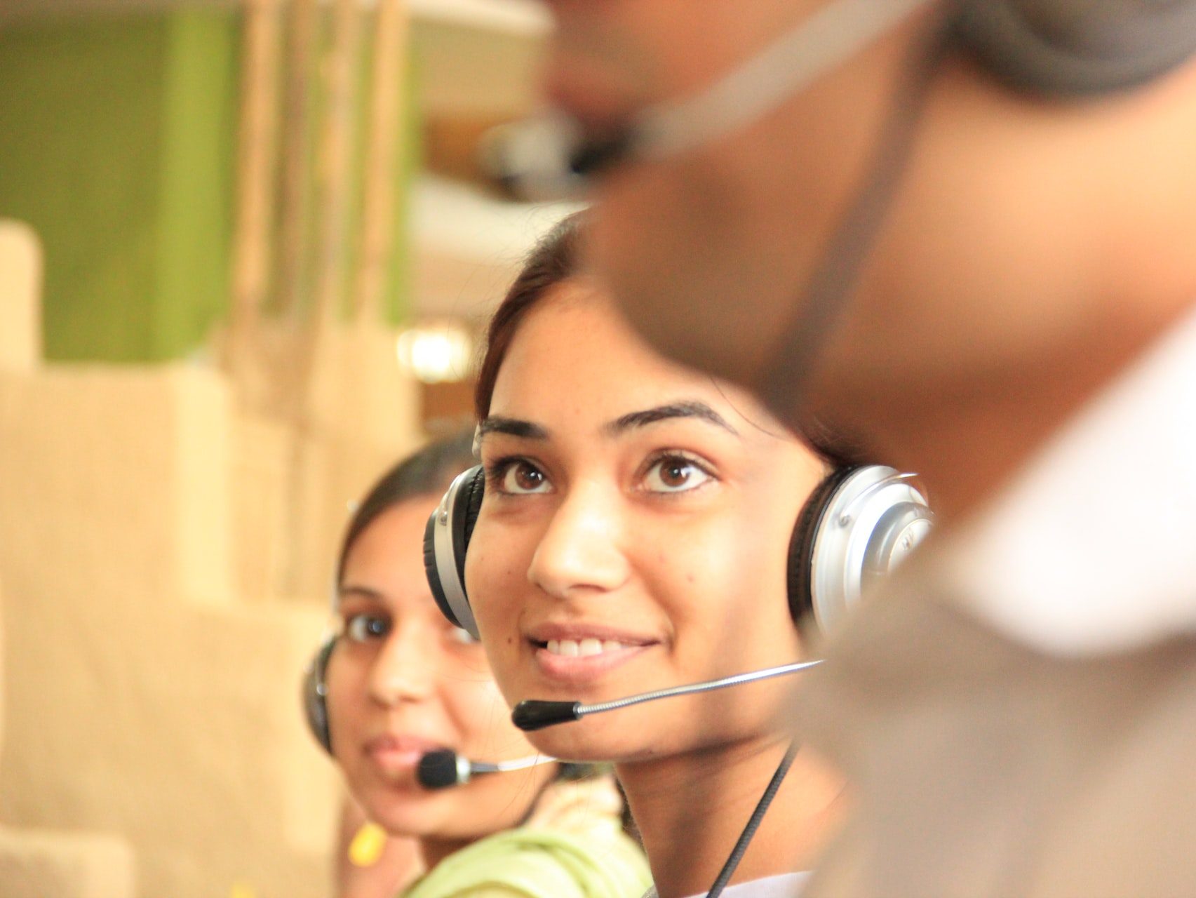 woman in black headphones holding black and silver headphones
